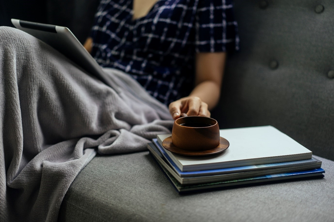 Person sitting on a sofa with a tablet and a cup of tea