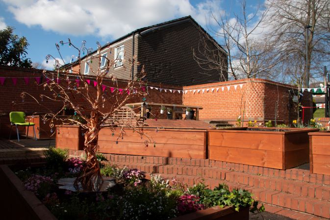 Garden with planters filled with flowers and a decorative metal tree sculpture