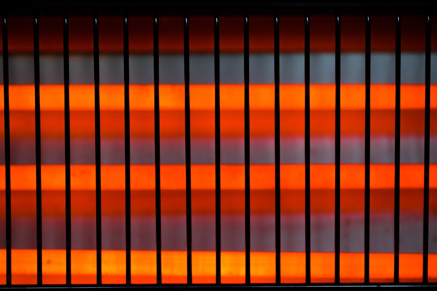 Close up of the heating element in an electric fire. The element is orange and glowing.